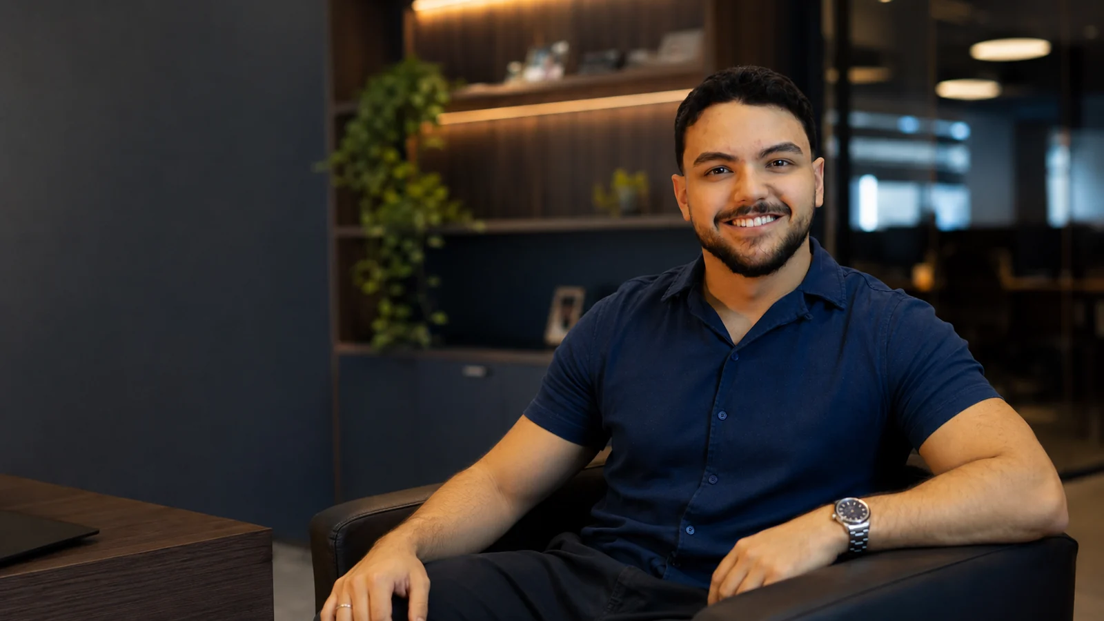Matheus Augusto sentado em um escritório contemporâneo, olhando para a câmera