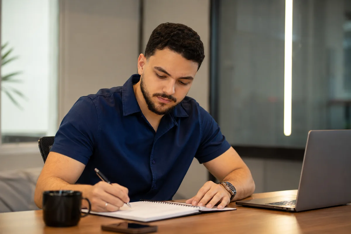 Matheus Augusto escrevendo um planejamento estratégico em um caderno